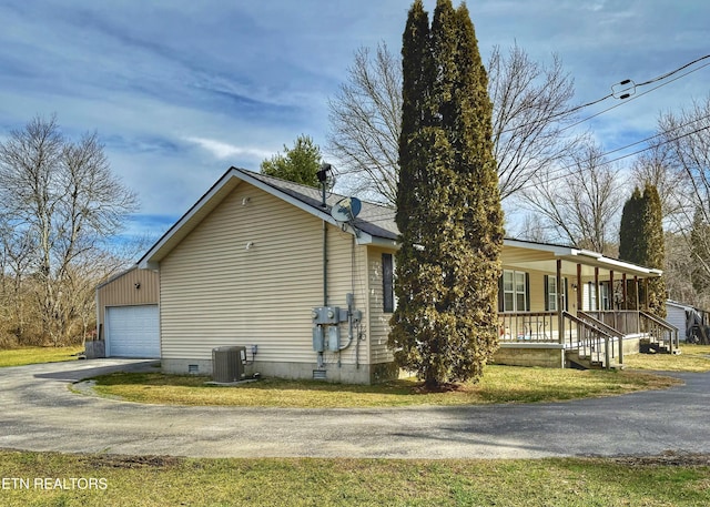 view of property exterior featuring covered porch, central AC, a garage, crawl space, and a lawn