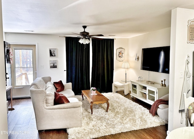 living area with a ceiling fan, visible vents, and wood finished floors