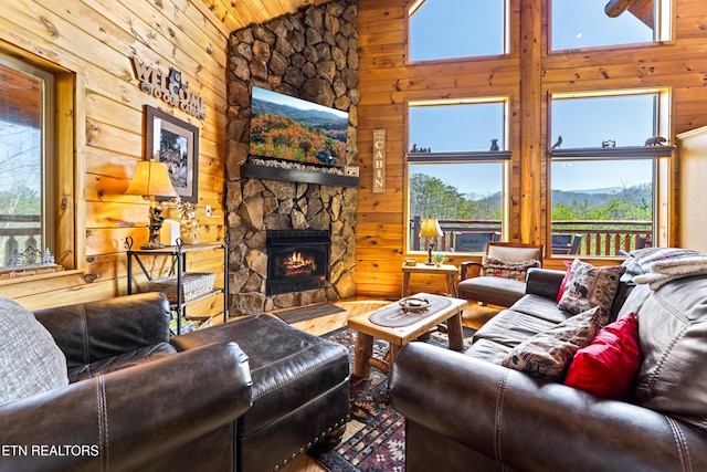 living area featuring high vaulted ceiling, a stone fireplace, and wood walls