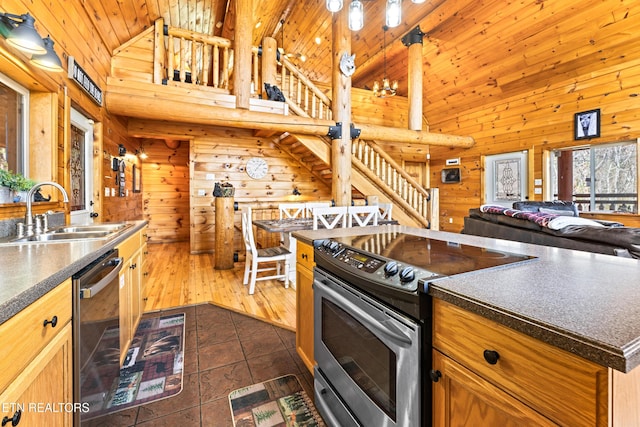 kitchen with a sink, stainless steel appliances, dark countertops, and wood walls