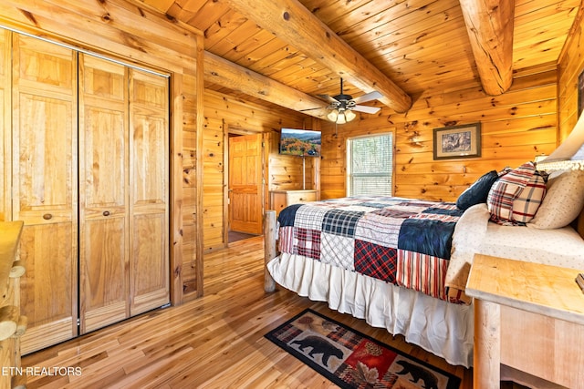 bedroom with beam ceiling, wood finished floors, wood walls, wood ceiling, and ceiling fan