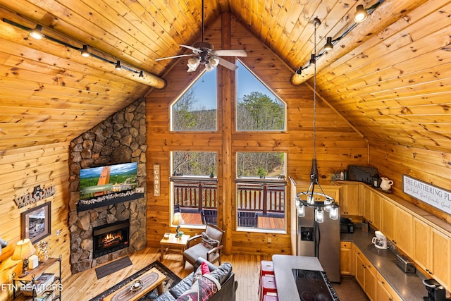 unfurnished living room featuring wooden walls, wood ceiling, a stone fireplace, a ceiling fan, and wood-type flooring