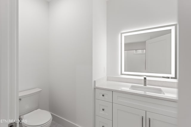 bathroom with toilet, vanity, and baseboards