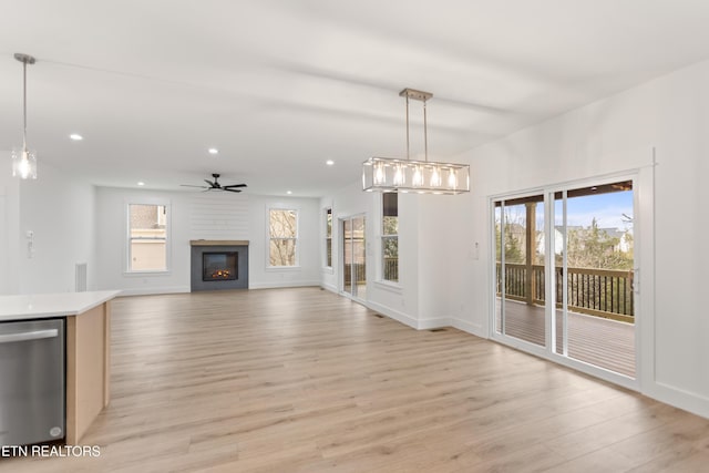 unfurnished living room featuring light wood finished floors, a glass covered fireplace, recessed lighting, and a ceiling fan