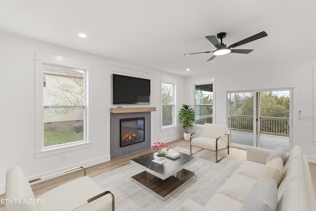 living area with wood finished floors, baseboards, a ceiling fan, recessed lighting, and a glass covered fireplace