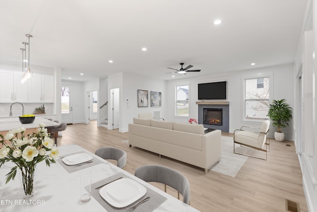 living area with visible vents, recessed lighting, light wood-style flooring, and a lit fireplace