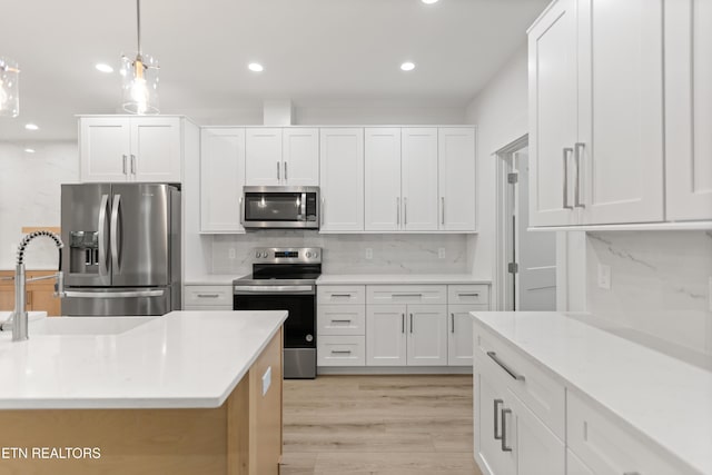 kitchen featuring a sink, tasteful backsplash, light wood-style floors, appliances with stainless steel finishes, and white cabinets