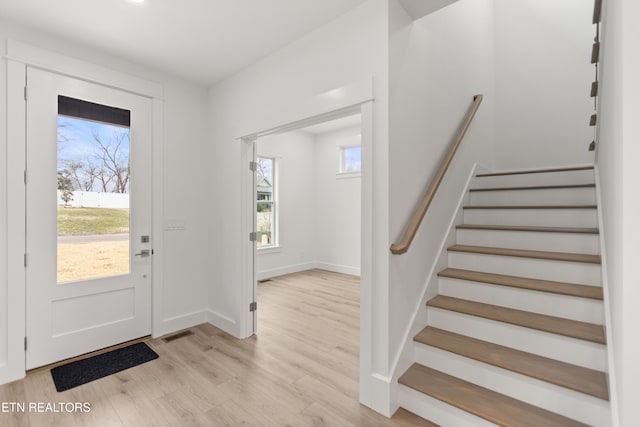 foyer featuring stairway, light wood-style flooring, baseboards, and visible vents