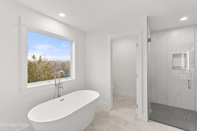 full bath with baseboards, recessed lighting, a freestanding bath, a shower stall, and toilet