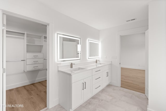 full bathroom with a sink, visible vents, baseboards, and double vanity