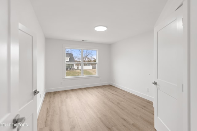 spare room featuring baseboards and light wood-style flooring