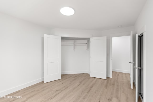 unfurnished bedroom featuring a closet, baseboards, and light wood-style floors