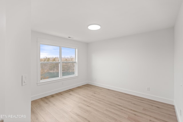 spare room featuring visible vents, light wood-style flooring, and baseboards