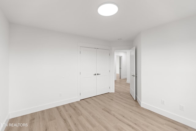 unfurnished bedroom featuring a closet, baseboards, and light wood finished floors