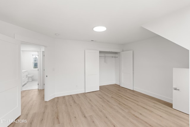 unfurnished bedroom featuring light wood-style flooring, baseboards, and a closet