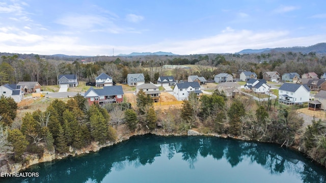 drone / aerial view with a residential view, a view of trees, and a water and mountain view