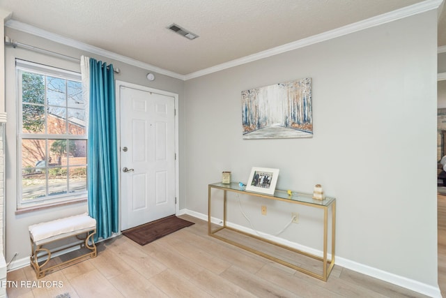 entrance foyer with wood finished floors, baseboards, visible vents, ornamental molding, and a textured ceiling