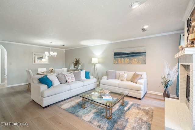 living room with arched walkways, light wood-style floors, a fireplace, and crown molding