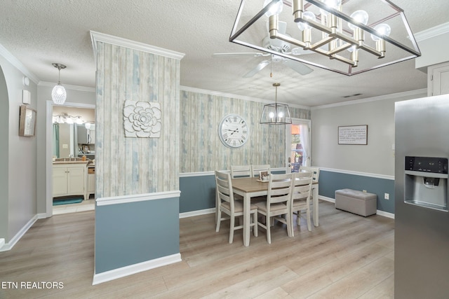 dining room with a textured ceiling, wood finished floors, baseboards, and ornamental molding