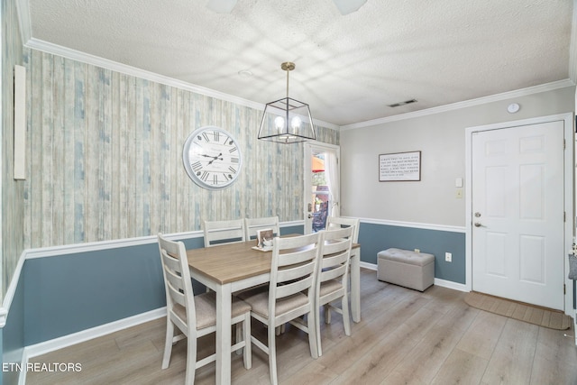 dining area with visible vents, ornamental molding, a textured ceiling, wood finished floors, and baseboards