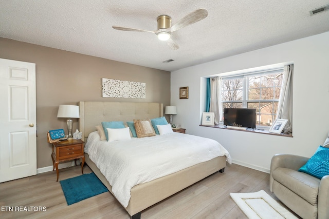 bedroom with visible vents, baseboards, light wood-style floors, and a textured ceiling