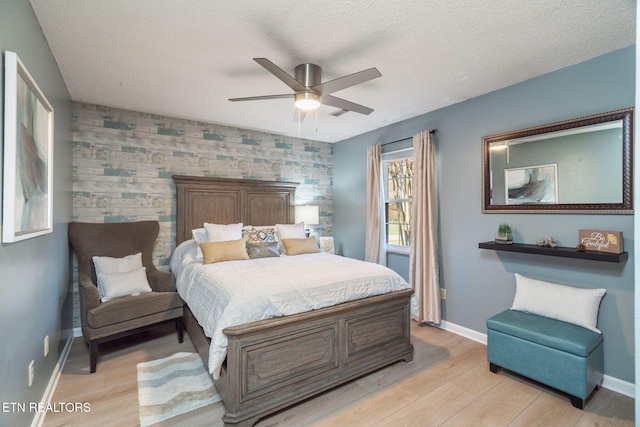 bedroom with baseboards, an accent wall, and light wood-style floors