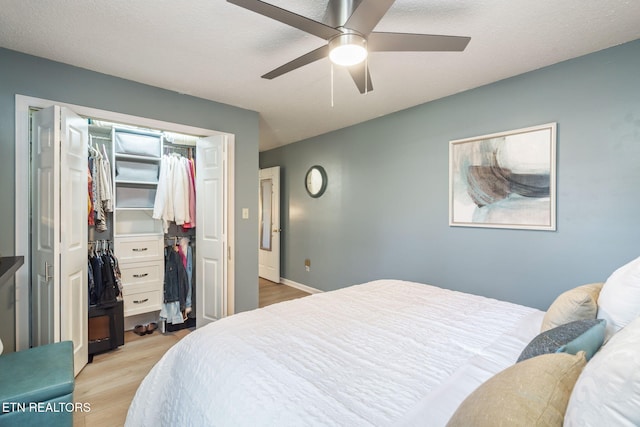 bedroom with a textured ceiling, light wood-style flooring, a closet, and ceiling fan