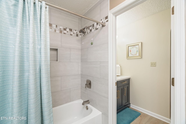 bathroom featuring vanity, wood finished floors, baseboards, a textured ceiling, and shower / tub combo with curtain