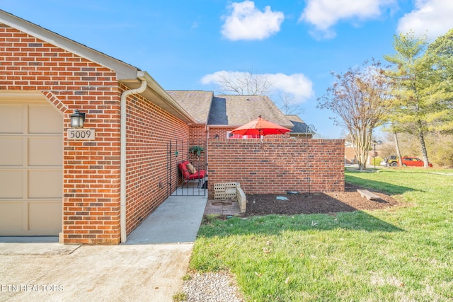 exterior space with brick siding, a lawn, an attached garage, and a shingled roof