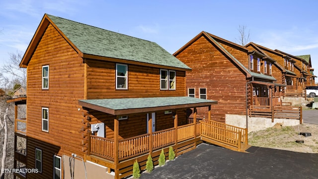 log cabin featuring a porch and roof with shingles