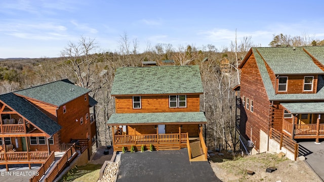 log-style house with covered porch, a shingled roof, a chimney, and log siding