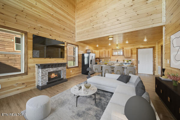 living area featuring visible vents, light wood-style flooring, a high ceiling, wood walls, and a fireplace