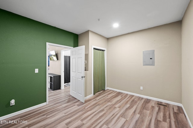 empty room featuring electric panel, baseboards, and wood finished floors