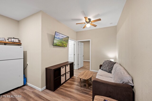 living area featuring light wood-style flooring, baseboards, and ceiling fan