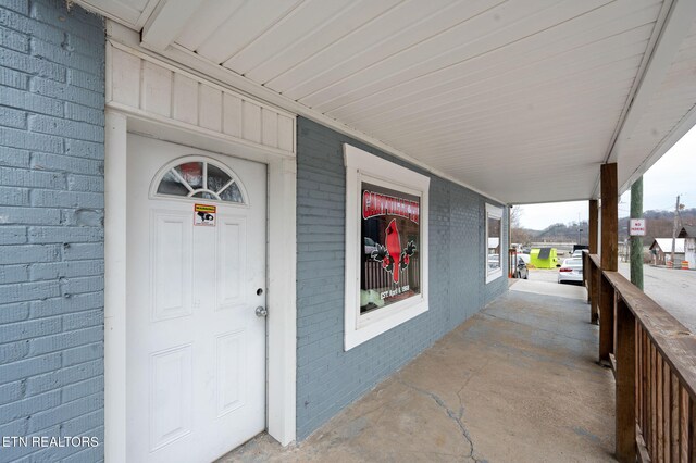 entrance to property with brick siding and a porch