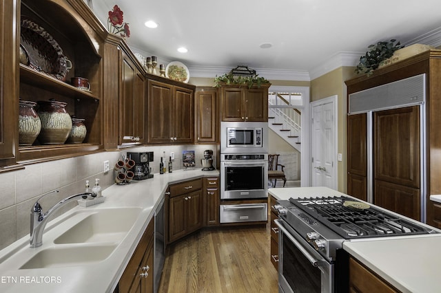 kitchen with light countertops, a warming drawer, built in appliances, and a sink