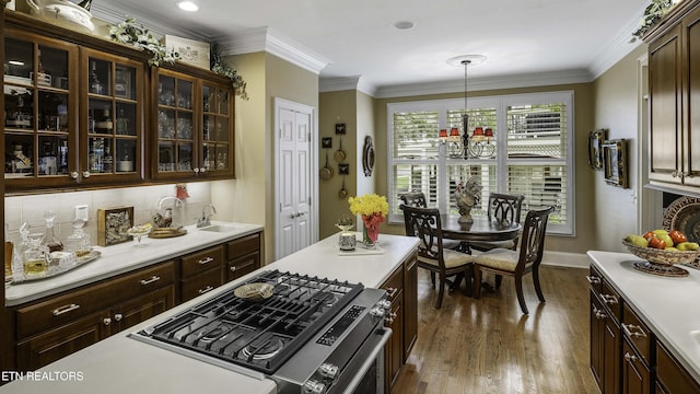 kitchen with crown molding, glass insert cabinets, wood finished floors, and light countertops