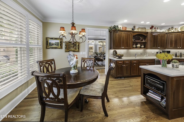 dining room featuring light wood-type flooring, recessed lighting, crown molding, baseboards, and a chandelier