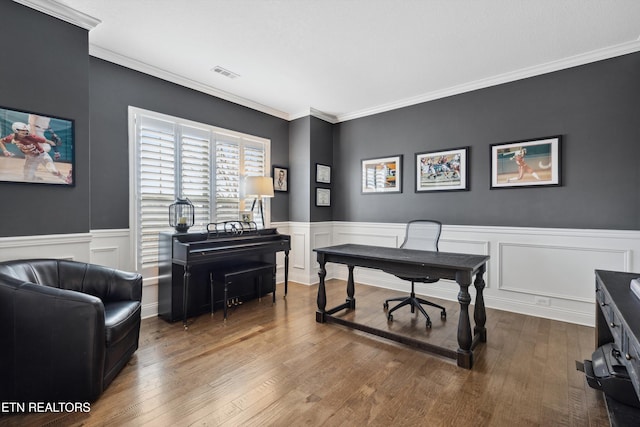 office area featuring wainscoting, visible vents, wood finished floors, and ornamental molding