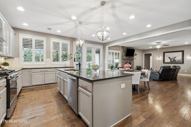 kitchen featuring dark wood finished floors, stainless steel appliances, a sink, and a stone fireplace