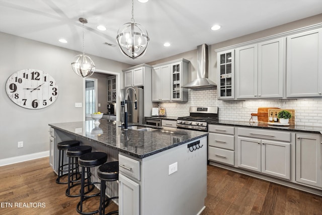 kitchen with appliances with stainless steel finishes, a sink, wall chimney range hood, and dark wood-style floors