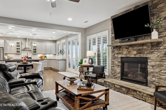 living area with a fireplace, light wood finished floors, recessed lighting, visible vents, and ceiling fan