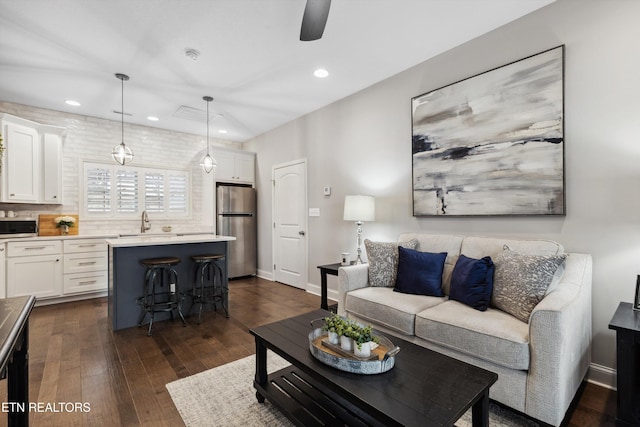 living area featuring baseboards, dark wood finished floors, a ceiling fan, and recessed lighting