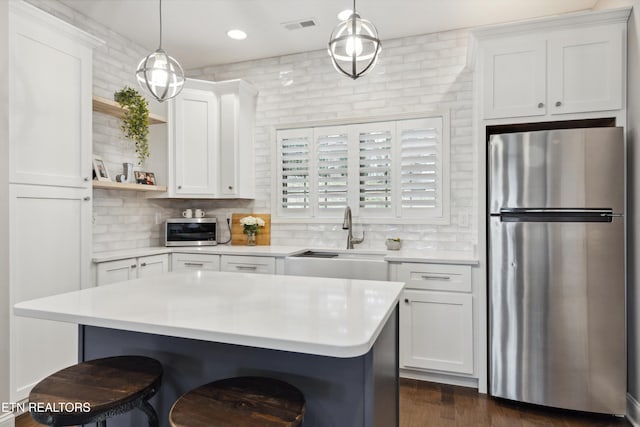 kitchen with stainless steel appliances, a sink, visible vents, light countertops, and open shelves