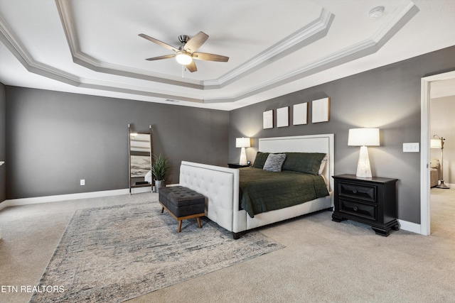 bedroom with ornamental molding, a tray ceiling, carpet flooring, and baseboards