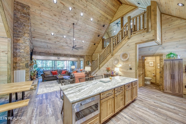 kitchen featuring light wood-style floors, stainless steel microwave, and wooden walls