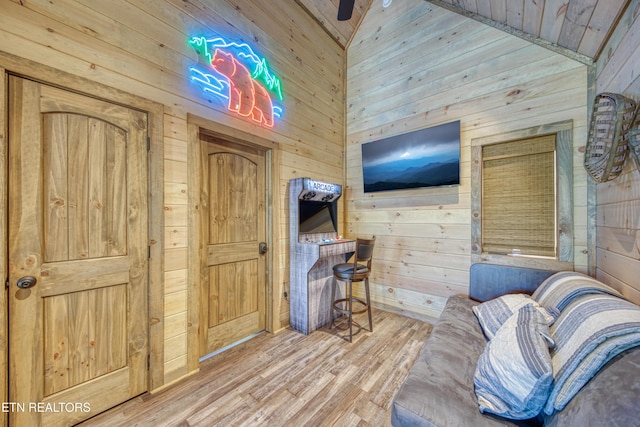 living area with wood walls, ceiling fan, and wood finished floors