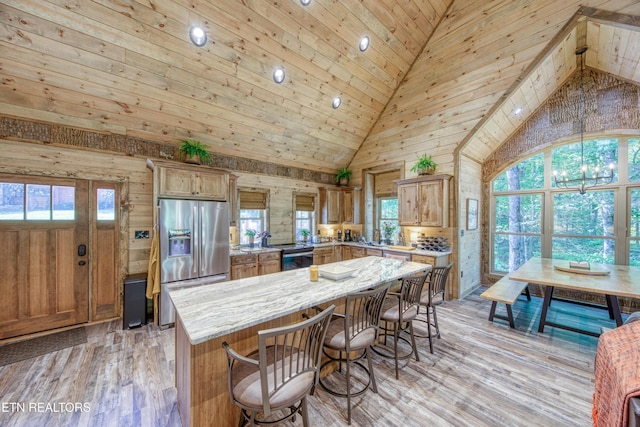 kitchen with light wood-style floors, a healthy amount of sunlight, a kitchen island, and stainless steel fridge with ice dispenser