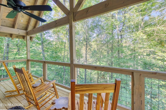 wooden deck with a ceiling fan and a view of trees