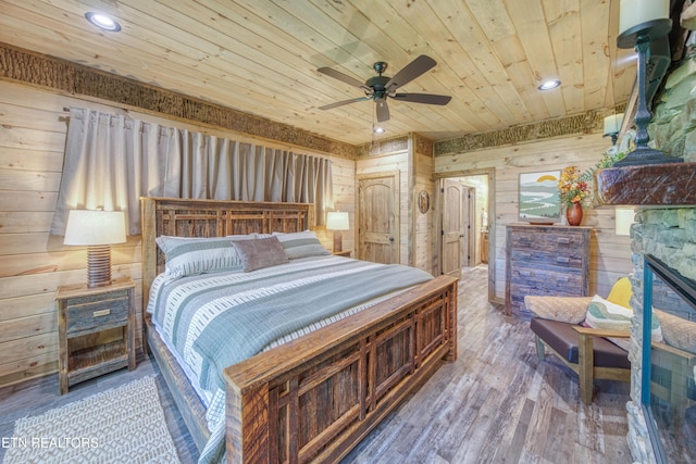 bedroom featuring wood ceiling, wood finished floors, wood walls, a fireplace, and recessed lighting